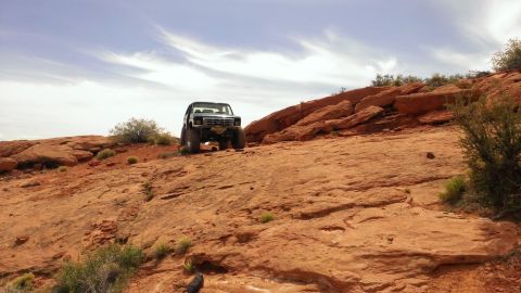 1994 Ford Bronco - Ford Bronco navigating challenging off-road terrain under a partly cloudy sky.