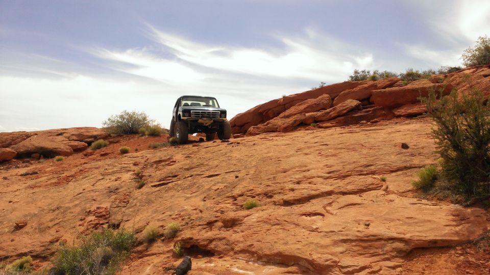 Ford Bronco climbing a steep, rocky hill in a desert landscape