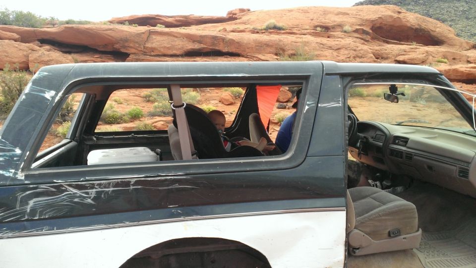 1990s Ford Bronco interior, side view, showing baby in car seat and dashboard