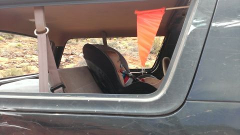 1994 Ford Bronco - A baby is secured in a car seat inside a vehicle, with an orange flag attached to the roof.