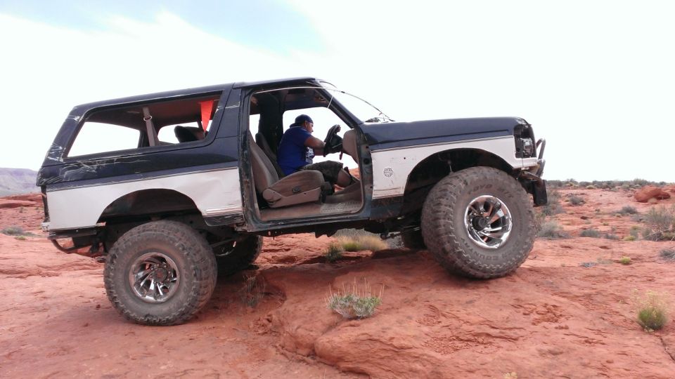 1994 Ford Bronco, doors removed, driving off-road in desert terrain