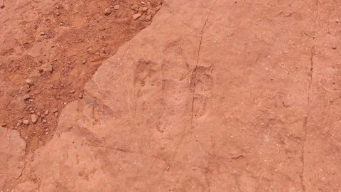 1994 Ford Bronco - Fossilized dinosaur footprints are visible in the red sandstone, indicating ancient life.