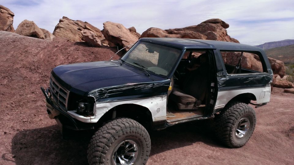 Off-road Bronco with open door, parked on rocky terrain