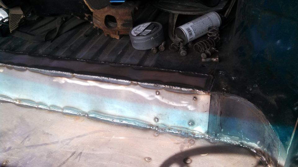 Vehicle interior floor with fresh welds and repair patches, tools and spray can visible