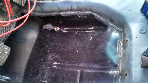 1979 Ford Bronco - The interior floor of a vehicle shows exposed metal and wiring, with visible pedals.