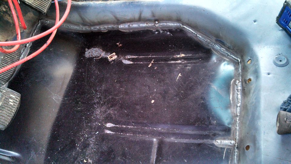 Vehicle interior floor with exposed metal, wiring, and pedals