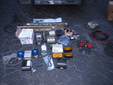 1991 Ford LTD Crown Victoria - Various components for emergency vehicle lighting and electrical systems are displayed on the ground.