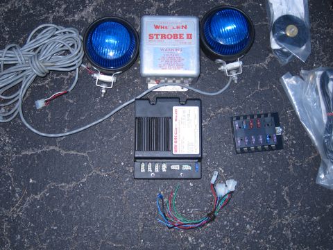 1991 Ford LTD Crown Victoria - Components of a Whelen Strobe II emergency light system are laid out on a dark, textured surface.