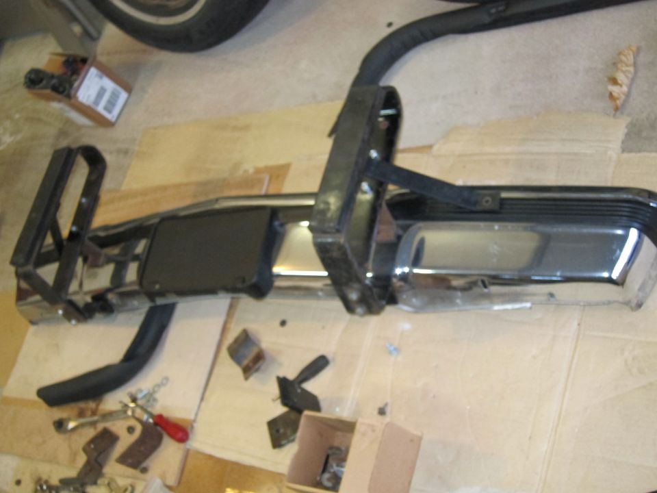 Chrome bumper with black trim and mounting hardware on cardboard