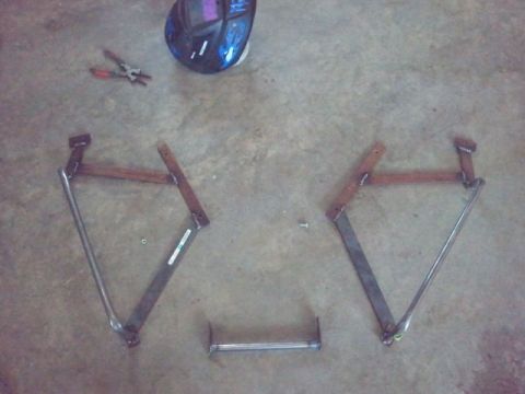 1995 Ford F-150 - Metal brackets and a connecting bar are laid out on a concrete floor, alongside a welding mask and pliers, suggesting a fabrication or repa…