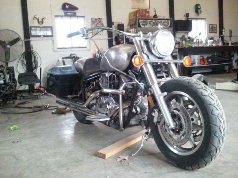 1995 Ford F-150 - A custom motorcycle sits in a workshop, appearing to be in the process of modification or assembly.