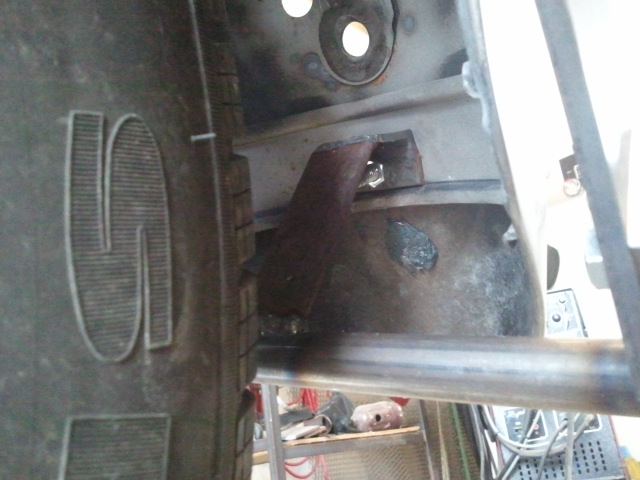Close-up of a truck's frame and tire, showing metal brackets and a bolted connection