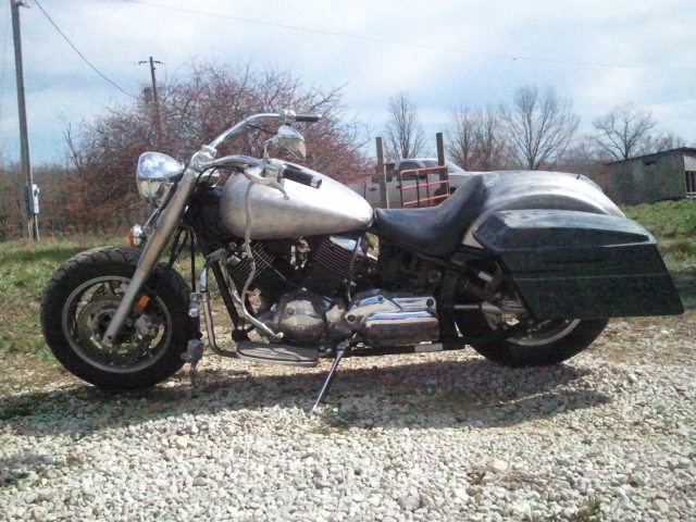 Silver motorcycle with black saddlebags and chrome accents parked on gravel
