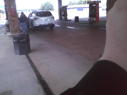 2003 Ford Crown Victoria - A white SUV is parked at a gas station with the driver's door open.