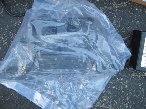 1991 Ford LTD Crown Victoria - A black plastic part is sealed in a plastic bag, with a label visible on a separate box.
