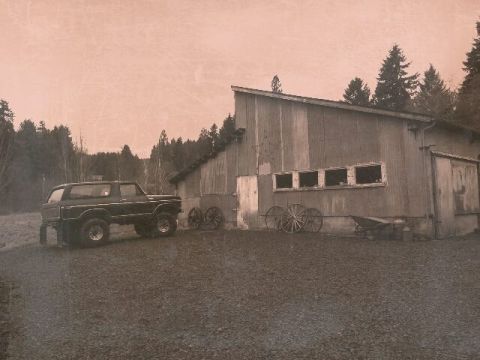 1979 Ford Bronco - A classic Ford Bronco sits outside a rustic barn, surrounded by trees and farm equipment.