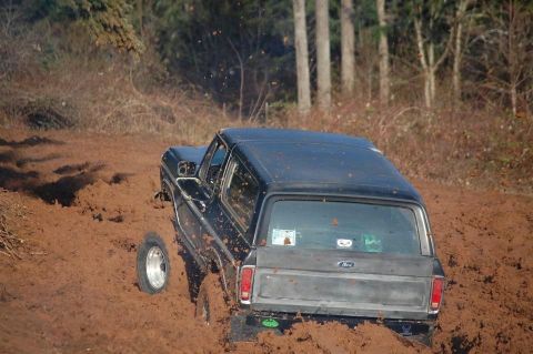 1979 Ford Bronco - This classic Ford Bronco is deep in the mud, with its rear end visible as it struggles to get traction.