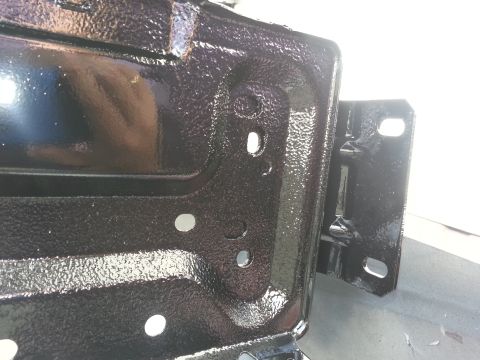 1994 Ford Bronco - Close-up of a black metal bracket, likely a vehicle part, with a textured finish.