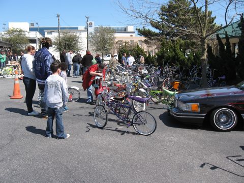 1994 Ford Bronco - A gathering of people with numerous bicycles and a lowrider car on a sunny day.
