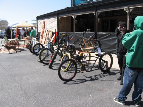 1994 Ford Bronco - A variety of custom bicycles are displayed outdoors near a building with people observing.