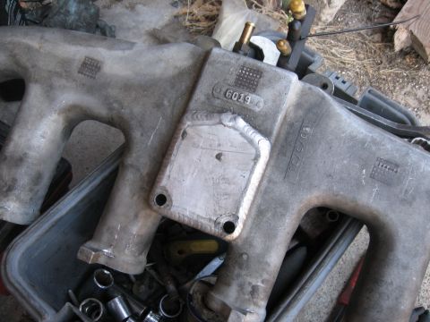 1981 Ford Bronco - Two aluminum intake manifolds are shown, one with a freshly welded plate and fittings. Tools are visible below.