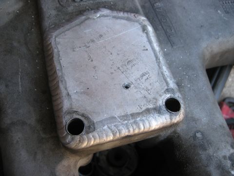 1981 Ford Bronco - A close-up view of a welded metal plate on an engine part, with visible bolt holes and a website logo.