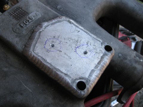 1981 Ford Bronco - A close-up view of a metal part with a welded plate and newly drilled holes, possibly for modification or repair.