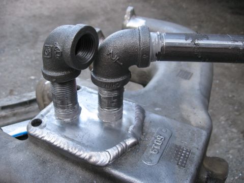 1981 Ford Bronco - Close-up of a custom intake manifold a welded plate with two pipe fittings attached.