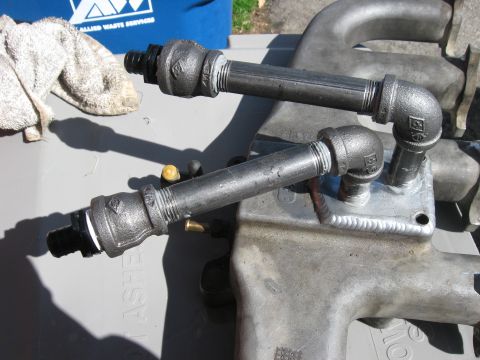 1981 Ford Bronco - Custom metal pipework is attached to an engine intake manifold, with a towel and blue fabric in the background.