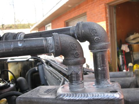 1981 Ford Bronco - Custom exhaust pipes made from black iron fittings and pipe, welded onto an engine component.