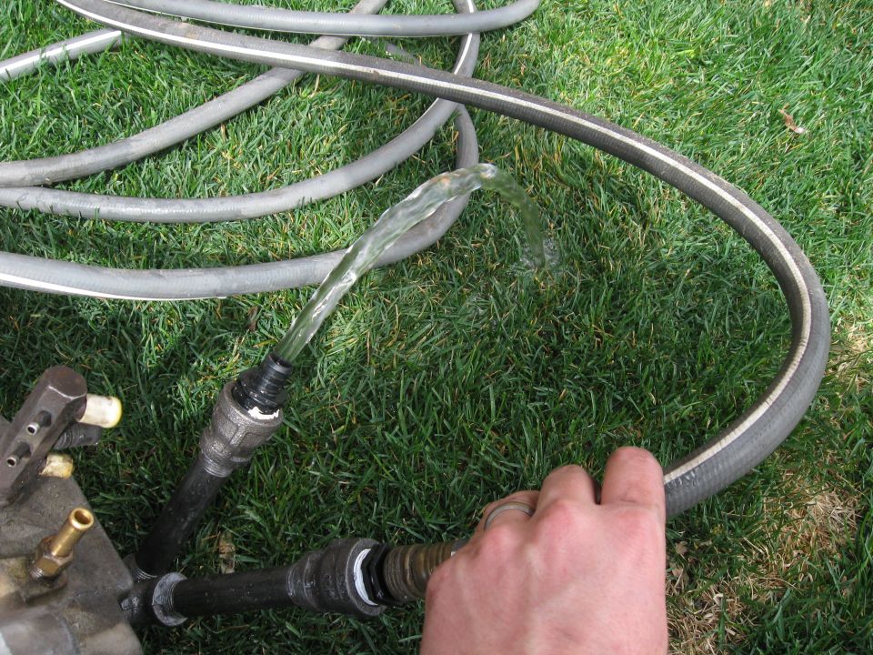 hand holding hose connected to plumbing with water running
