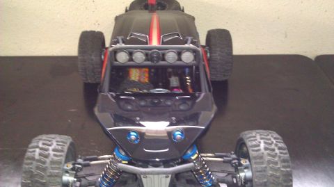 1996 Ford Bronco - A black remote control buggy with a red stripe is viewed from the front, showing its off-road tires and light bar.