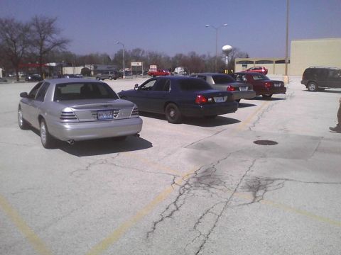 2003 Ford Crown Victoria - A silver 2003 Ford Crown Victoria is parked in a lot with other vehicles.
