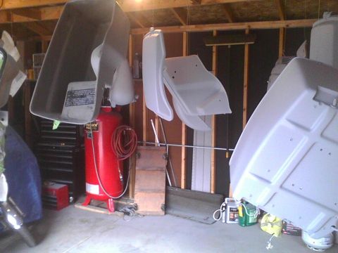 2003 Ford Crown Victoria - Various car body parts are suspended and appear to be undergoing a painting process in a garage setting.