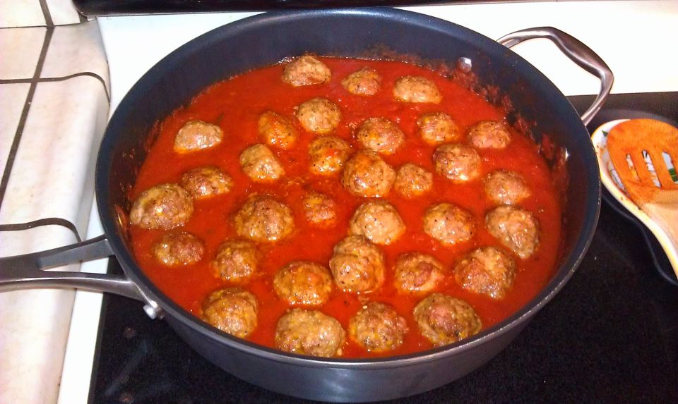 Meatballs simmering in marinara sauce in a large skillet