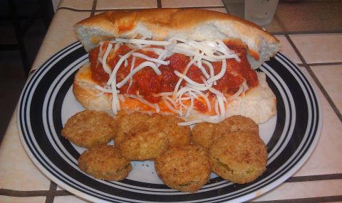 1989 Ford Bronco - A close-up shot shows a hearty meatball sub served with a side of crispy fried pickles on a black and white striped plate.