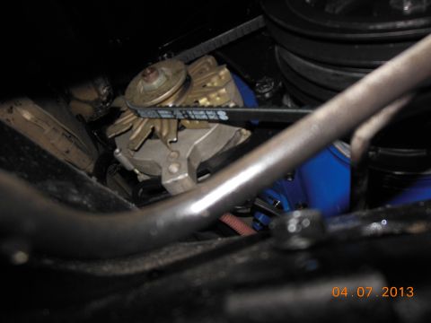 1979 Ford F-150 - Close-up view of an alternator and its drive belt, with a blue engine component in the background.