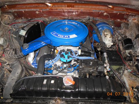 1979 Ford F-150 - Overhead view into the engine bay of a brown pickup showing a Ford V8 painted Ford blue, topped with a round blue air cleaner lid decaled "…