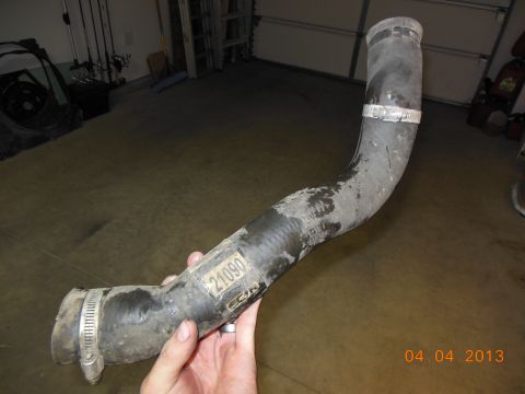 1979 Ford F-150 - A radiator hose with a visible part number is held up in a garage setting.
