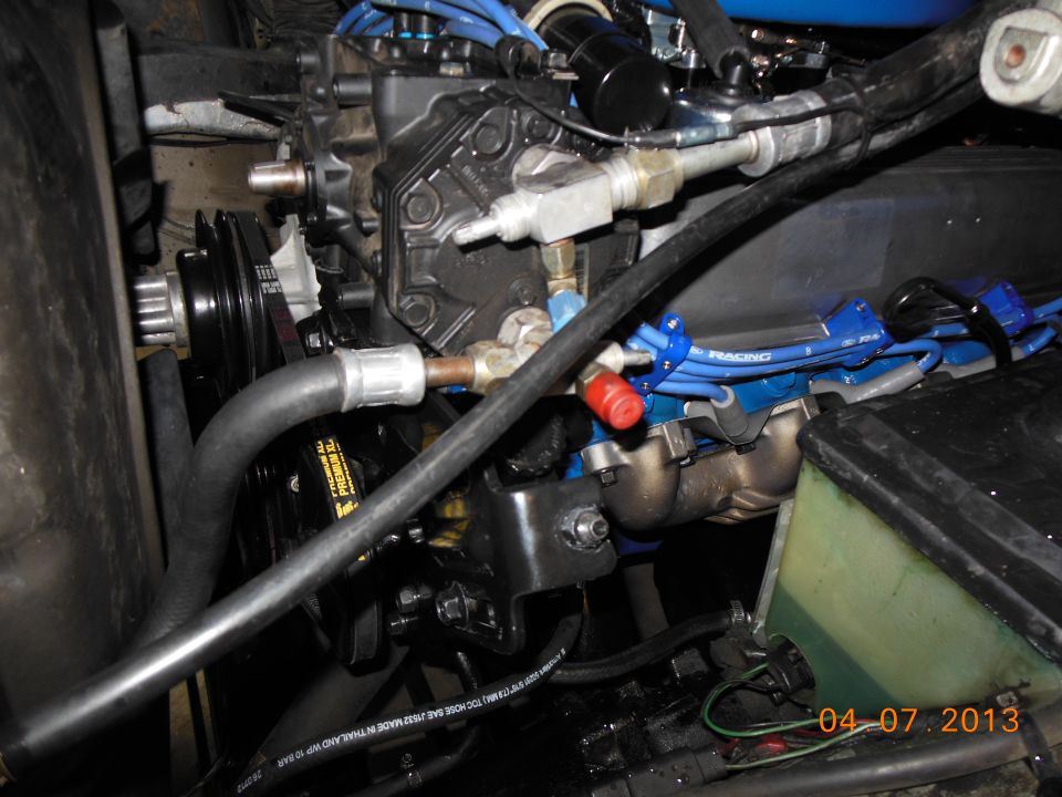 engine bay with V8 engine, blue spark plug wires, and hoses