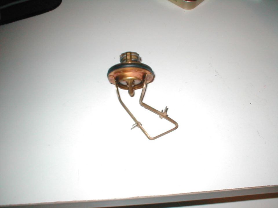 Thermostat part with copper and black rubber seal, on a white surface