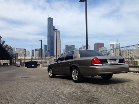 2005 Ford Crown Victoria - Rear view of a 2005 Ford Crown Victoria parked in an urban setting with a city skyline.