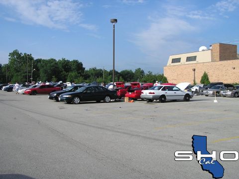 1993 Ford Taurus - A collection of vehicles are parked in a lot, with a white sedan prominently displayed with its hood open.