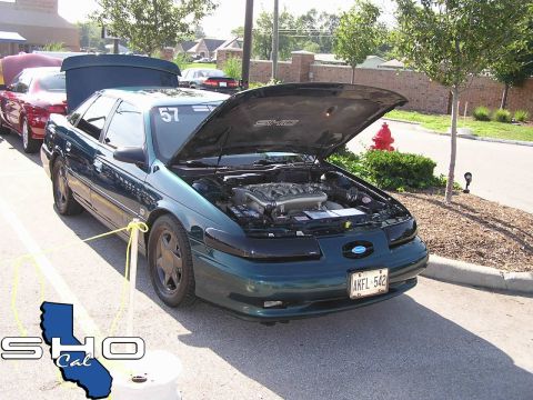 1993 Ford Taurus - A green 1993 Ford Taurus SHO is displayed with its hood open, the engine. Another vehicle is visible in the background.