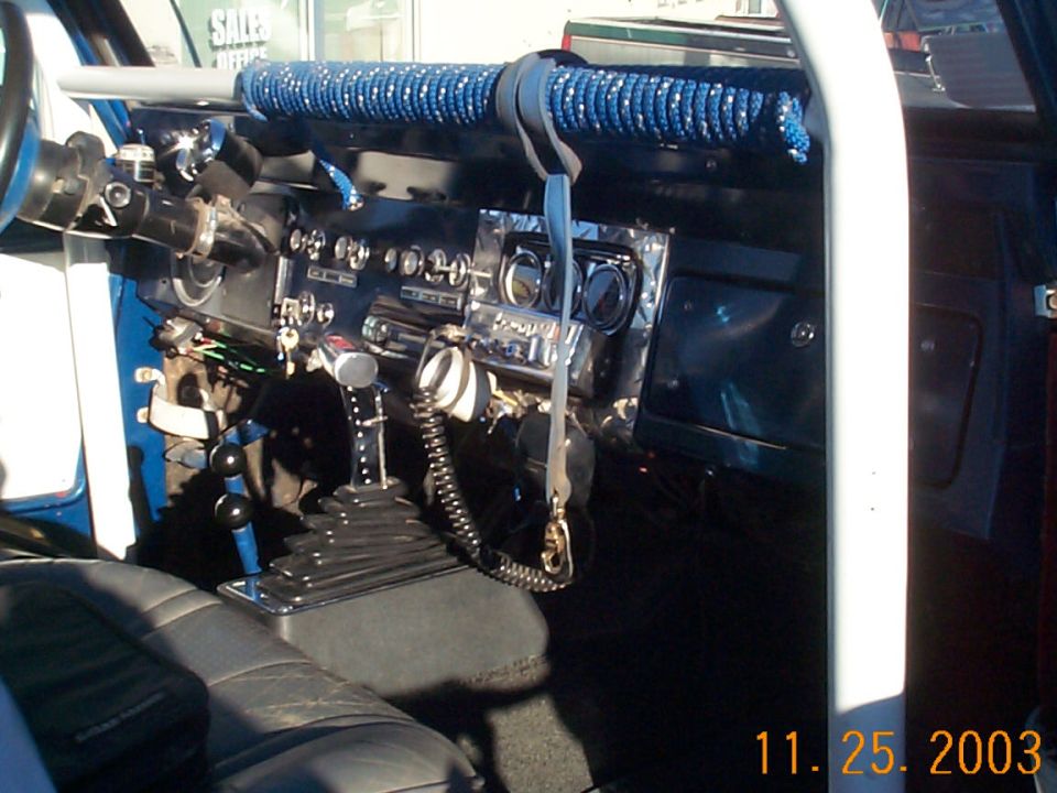 Custom Ford Bronco interior with padded roll cage, toggle-switch dash, CB mic, and dual floor shifters