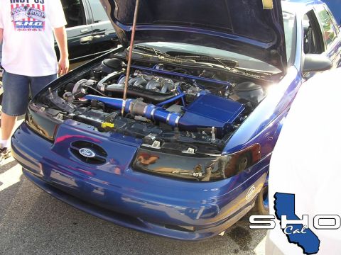 1993 Ford Taurus - A blue 1993 Ford Taurus is displayed with its hood open, revealing a customized engine bay.