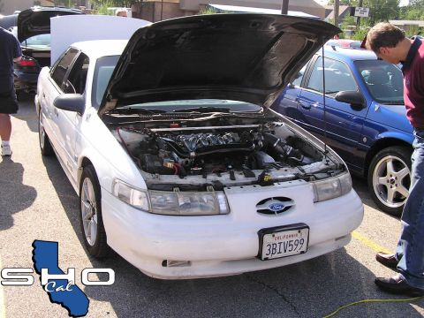 1993 Ford Taurus - A white 1993 Ford Taurus is parked with its hood open, revealing the engine compartment.