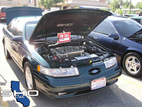1993 Ford Taurus - A green 1993 Ford Taurus SHO is parked next to a blue car, both with hoods open.