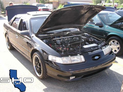 1993 Ford Taurus - A black 1993 Ford Taurus is displayed with its hood open, the engine bay. Another car is visible to the right.