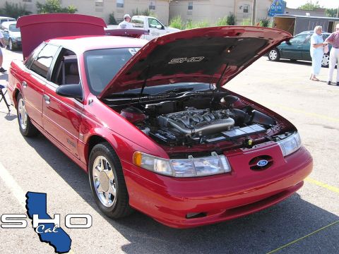 1993 Ford Taurus - A red 1996 Ford Taurus SHO is displayed with its hood open, its engine and a SHO logo on the underside of the hood.